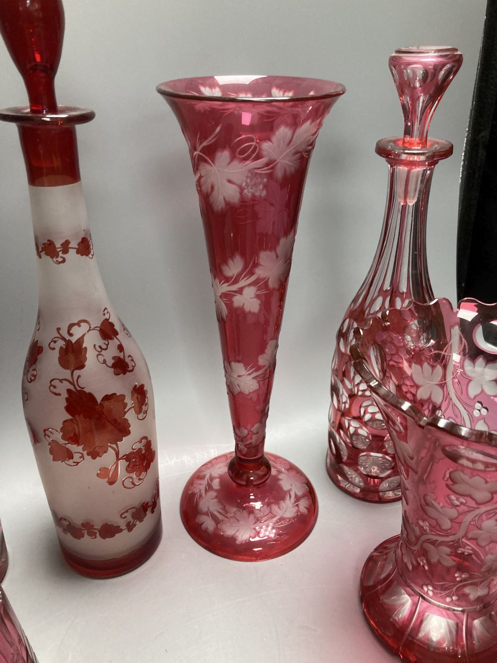 A collection of nine pieces of cranberry and ruby coloured glass, including a pair of decanters, two vases and a carafe and tumbler